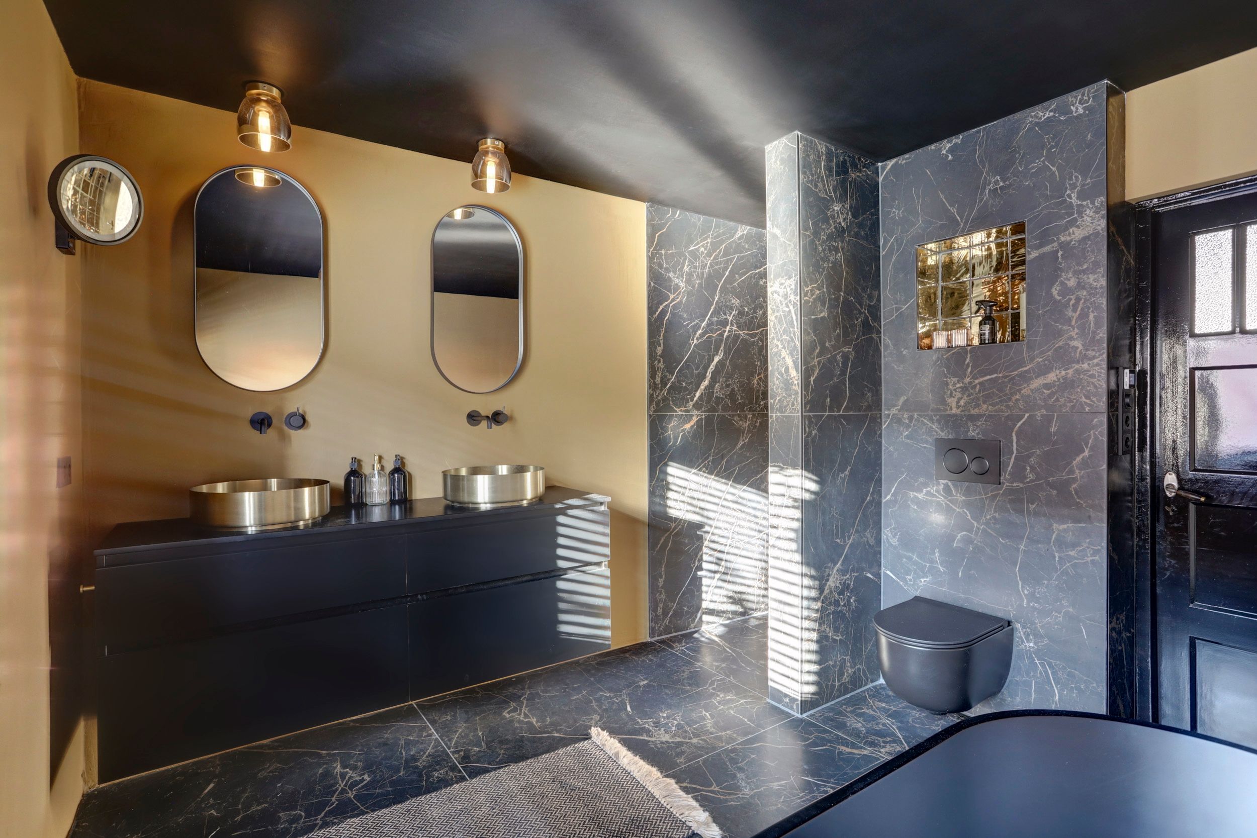 Zwart badmeubel met doorkijk naar de gouden douche bij Melissa