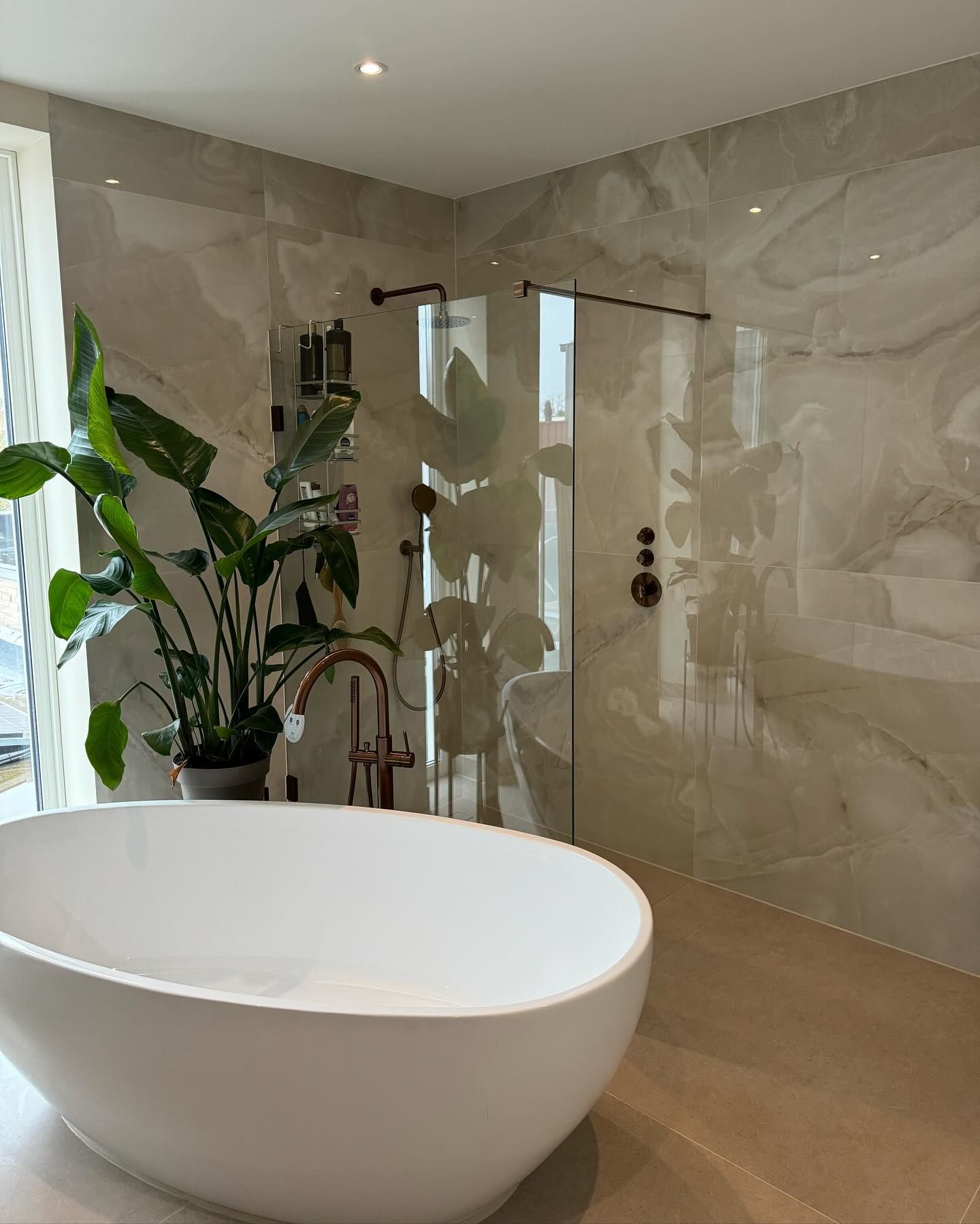 Badkamer van Sven met vrijstaand bad, koperen kranen en onyx-look wanden