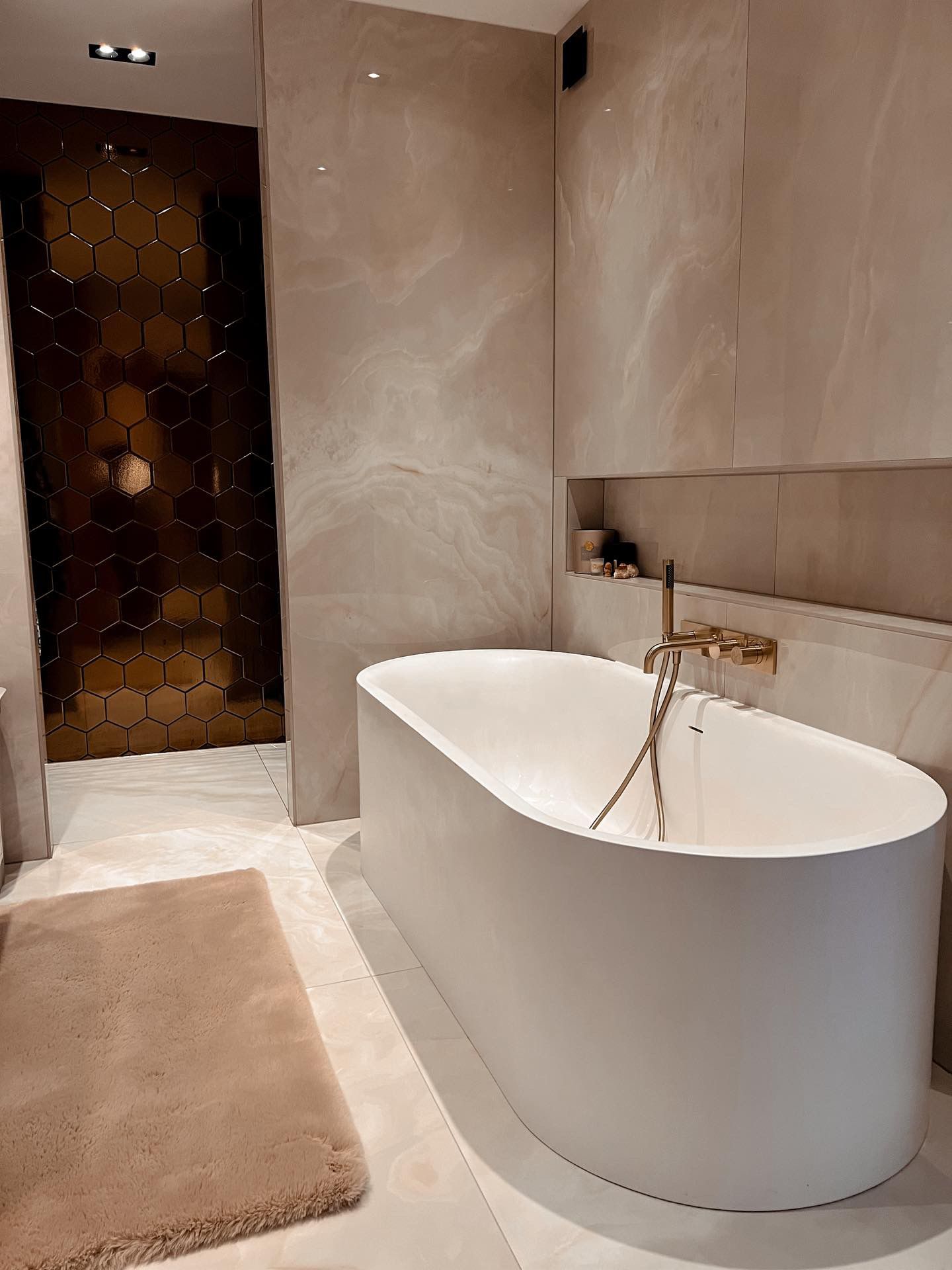 Luxe badkamer van Sarah van Soelen met gouden kranen, marmerlook tegels en een vrijstaand ligbad
